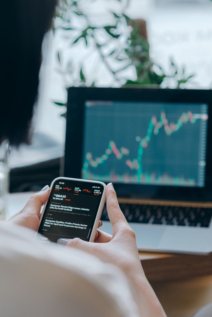 journey-02 Person using smartphone for stock market analysis at home office.